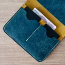 Kart ve para bölmeleri dolu halde sergilenen Camel – Petrol Lyra full grain deri pasaport cüzdanı, Noir & Co. el dikişli işçiliğiyle.